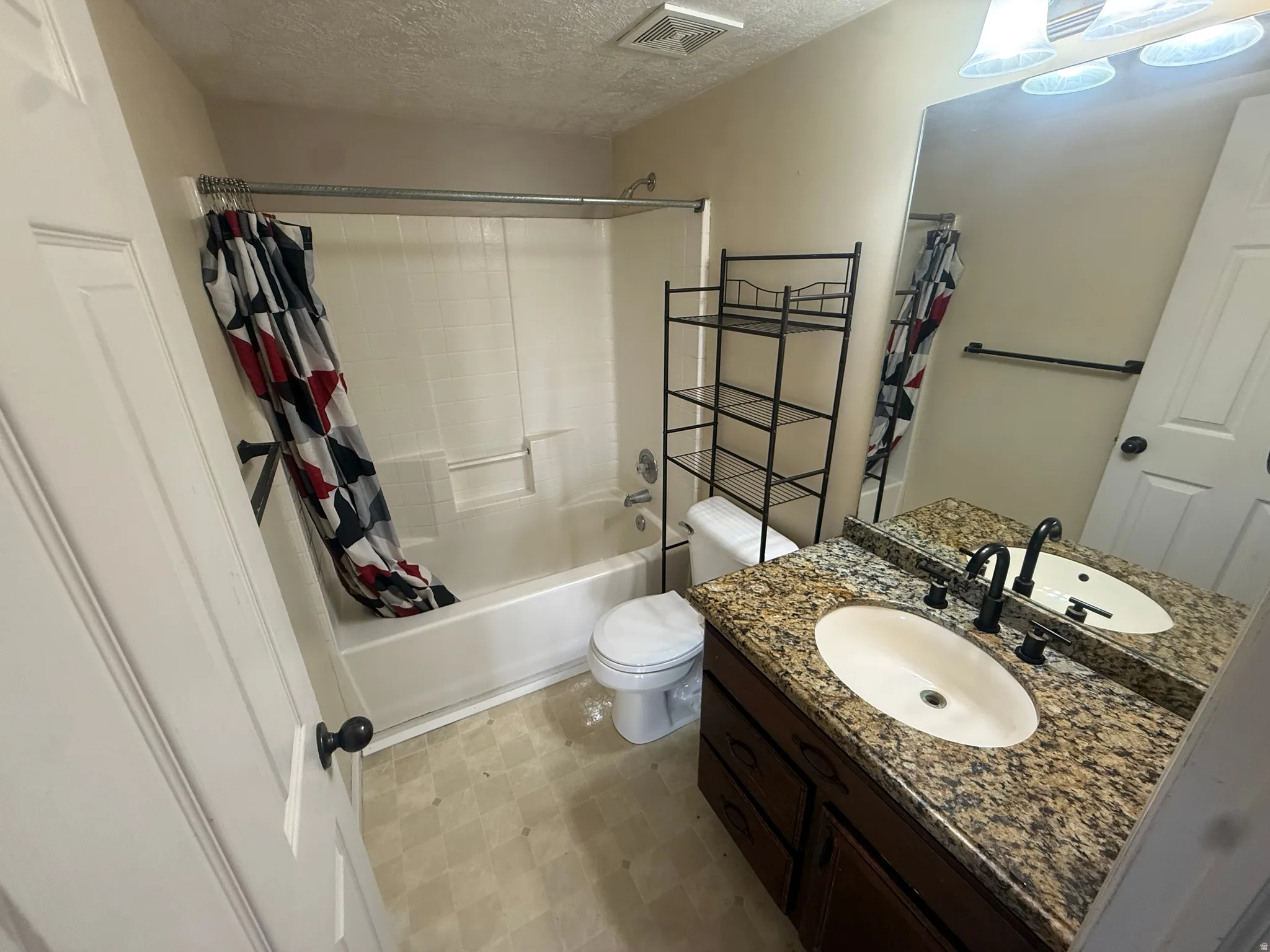 Bathroom featuring a vanity with a granite-style countertop, oval undermount sink, dark wood-finish cabinetry, and a full-width mirror