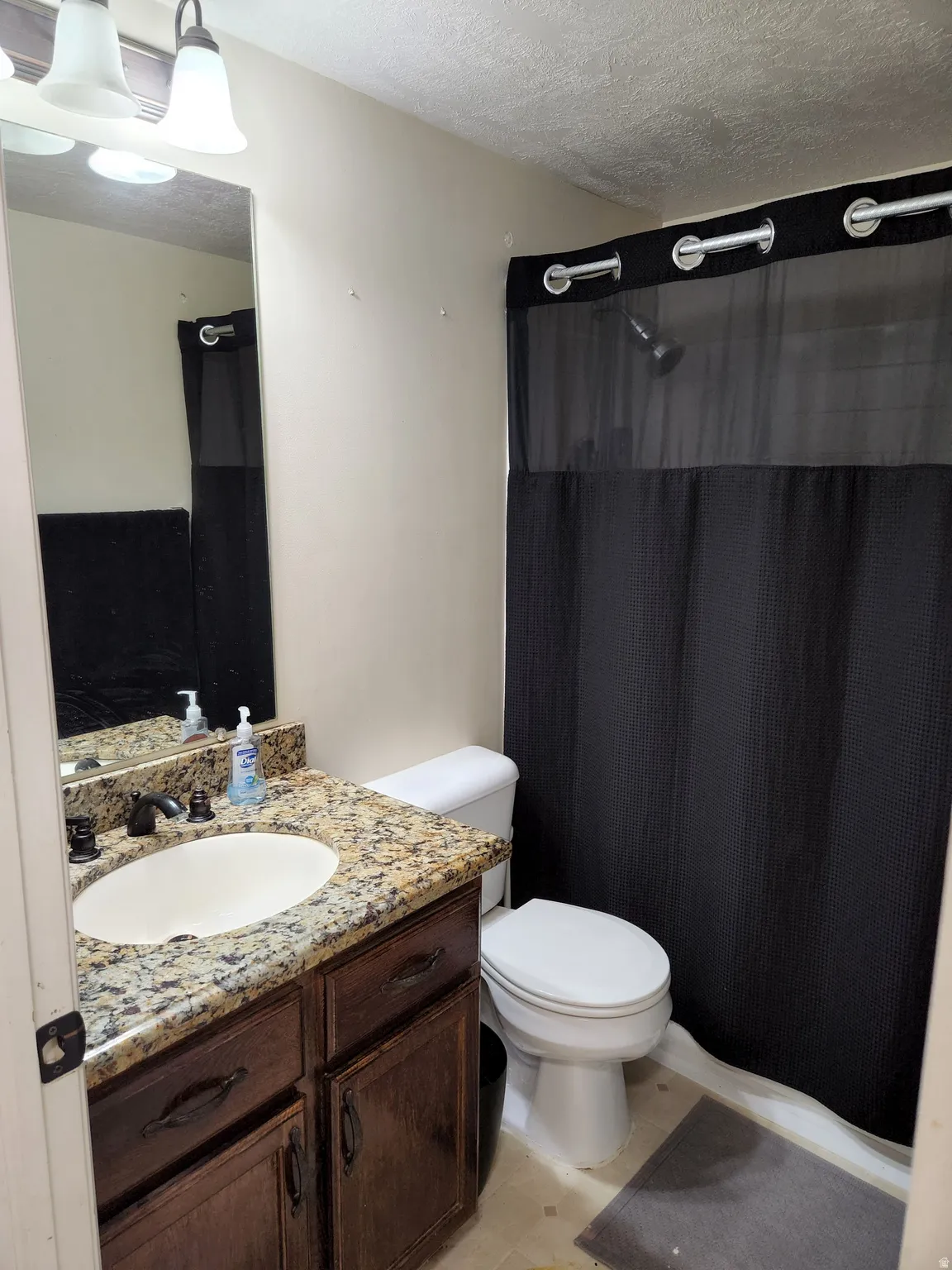 Full Bathroom featuring a vanity with a granite-style countertop, undermount sink, and dark wood-finish cabinetry