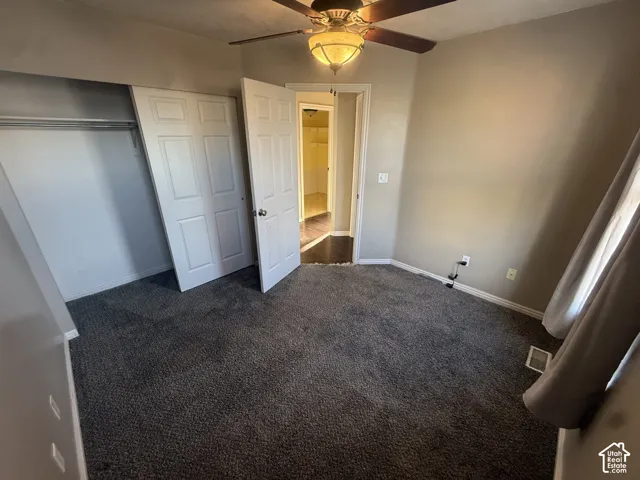 Built-in closet with bi-fold doors, overhead ceiling fan with light fixture, wall-to-wall carpeting