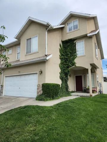 Two-story stucco exterior featuring a prominent covered entryway with an arched detail and attached 2 car garage