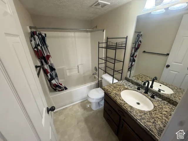 Bathroom featuring a vanity with a granite-style countertop, oval undermount sink, dark wood-finish cabinetry, and a full-width mirror
