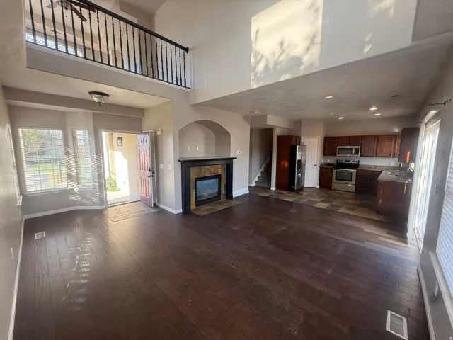 Two-story living area with wood-finish flooring and an open second-story hallway with a black spindle railing