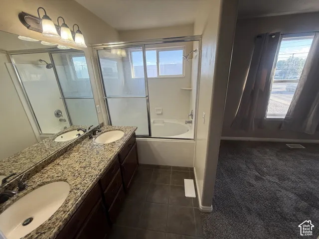 Dual vanity with speckled countertop, built-in cabinetry, and under-mount sinks