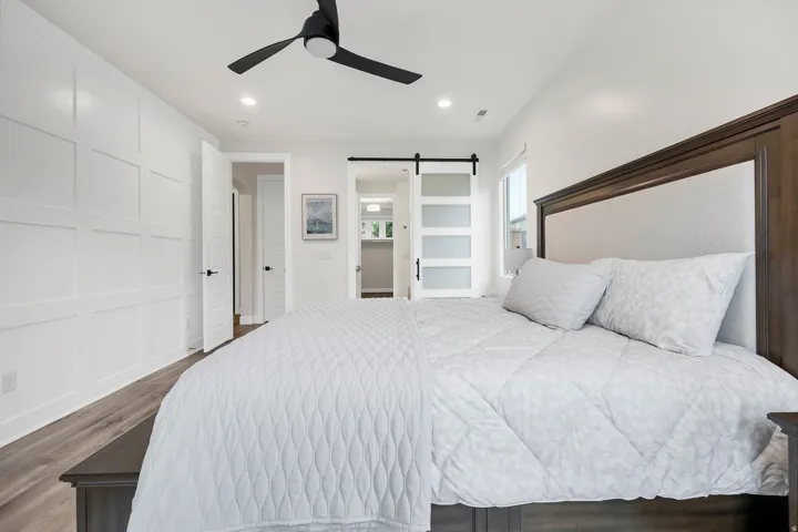 Spacious bedroom featuring wood-finish flooring and a contemporary black ceiling fan