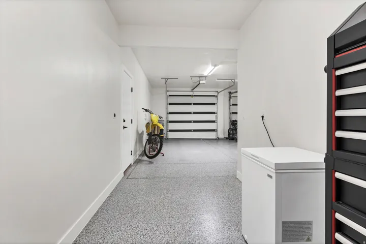 Spacious garage with epoxy flooring, white walls, overhead lighting, and white segmented garage doors