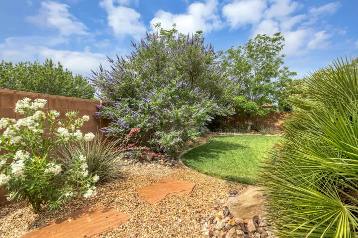 Expansive backyard featuring a manicured lawn, established landscaping, decorative gravel, and stepping stones