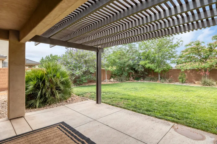Covered patio with a slatted pergola, offering an expansive concrete surface