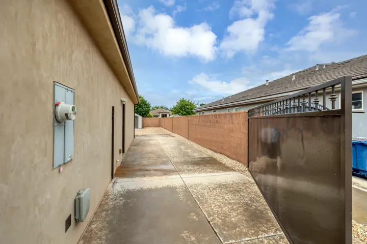 Concrete pathway with a metal gate, stucco exterior, and a block wall