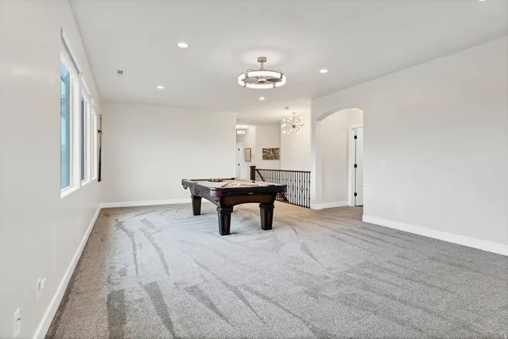 Spacious room featuring gray carpet, recessed lighting, and a contemporary ceiling fixture