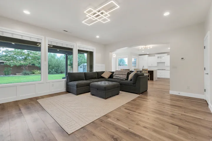 Spacious living area featuring expansive windows, wood-finish flooring, recessed lighting, and a contemporary ceiling fixture
