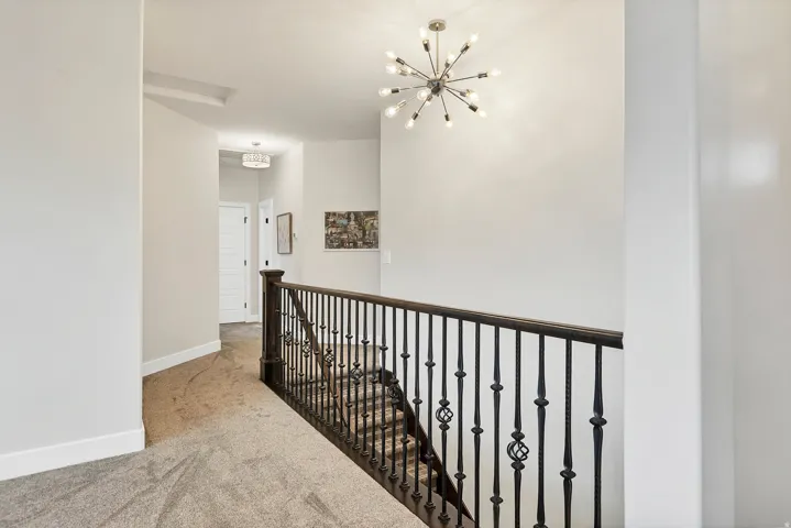 Upper-level landing featuring a contemporary sputnik chandelier and neutral carpeting
