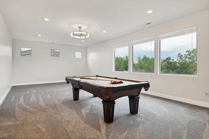 Spacious room featuring patterned carpet, recessed lighting, and a contemporary ceiling fixture