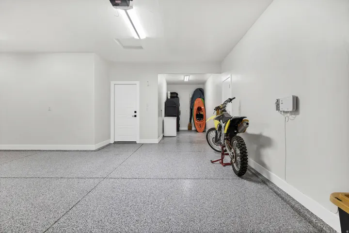 Spacious garage featuring a durable epoxy-coated floor, painted walls, built-in overhead lighting, and a white paneled entry door