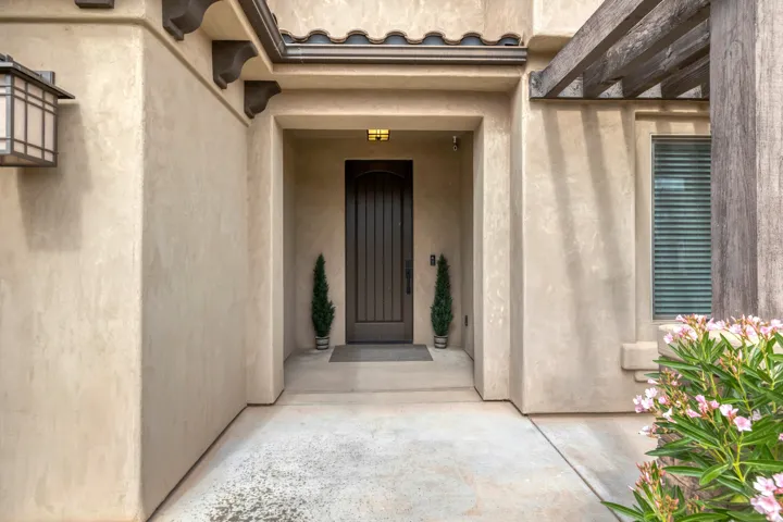 Recessed entry with a paneled wood-finish door, stucco exterior, decorative corbels, and a tile roofline