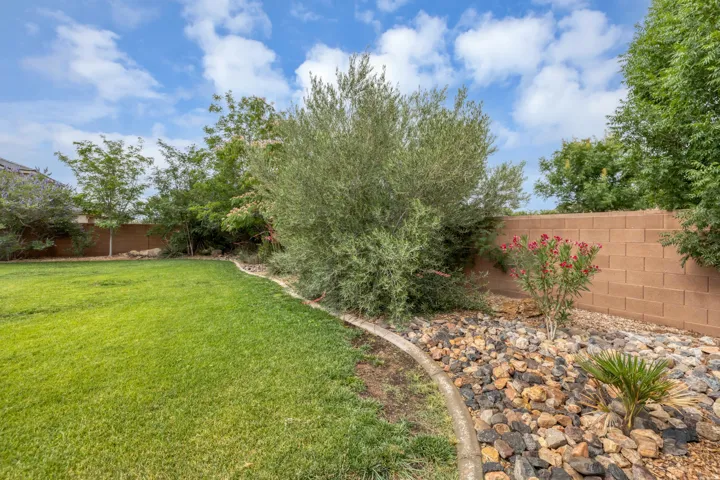Expansive backyard featuring a lush lawn, a mature shrub, and a decorative rock garden with flowering plants