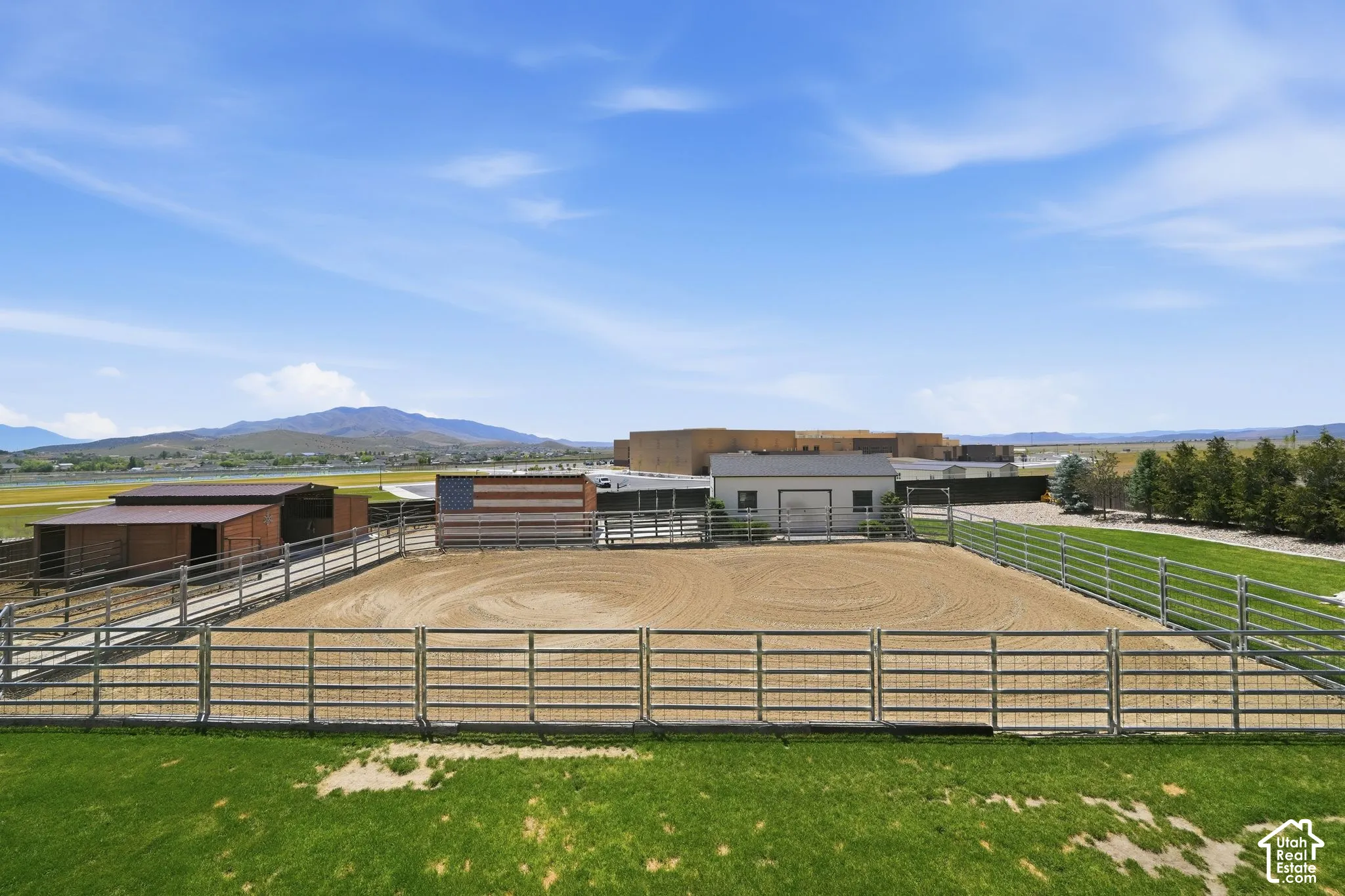 Expansive equestrian arena featuring a sand riding surface and metal fencing