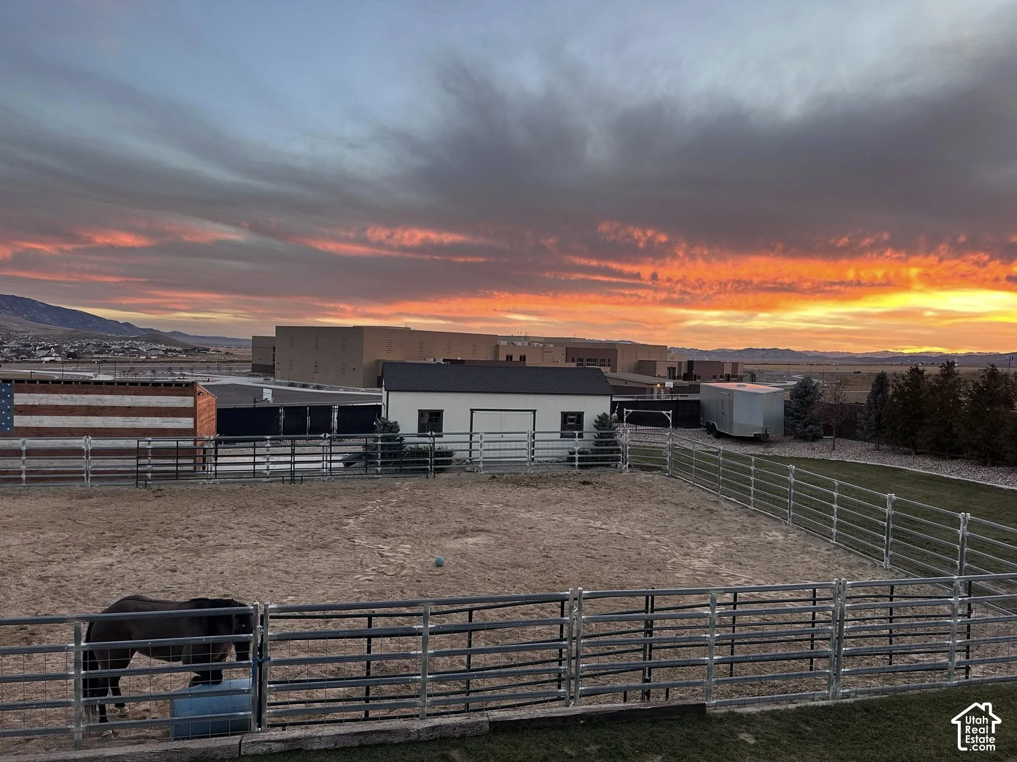 Expansive fenced equestrian arena with sand footing, accompanied by a dedicated outbuilding