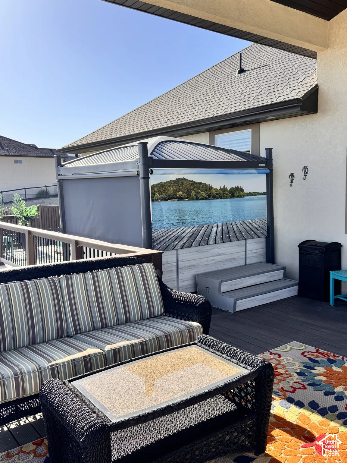 Spacious outdoor deck featuring dark composite decking, a built-in hot tub with steps, and a privacy screen