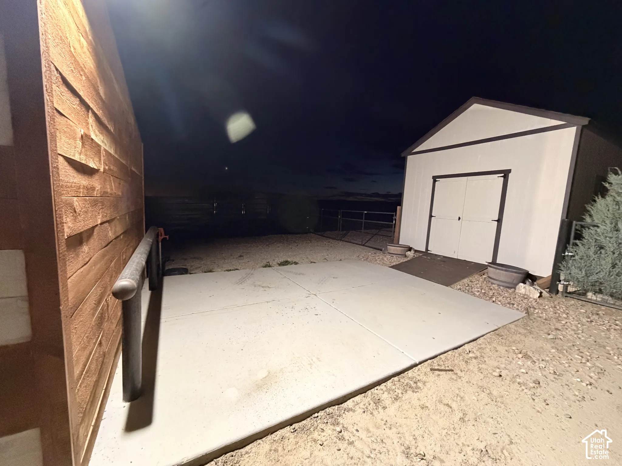 Exterior space featuring a concrete pad, a storage structure with double doors, and wood-finish siding