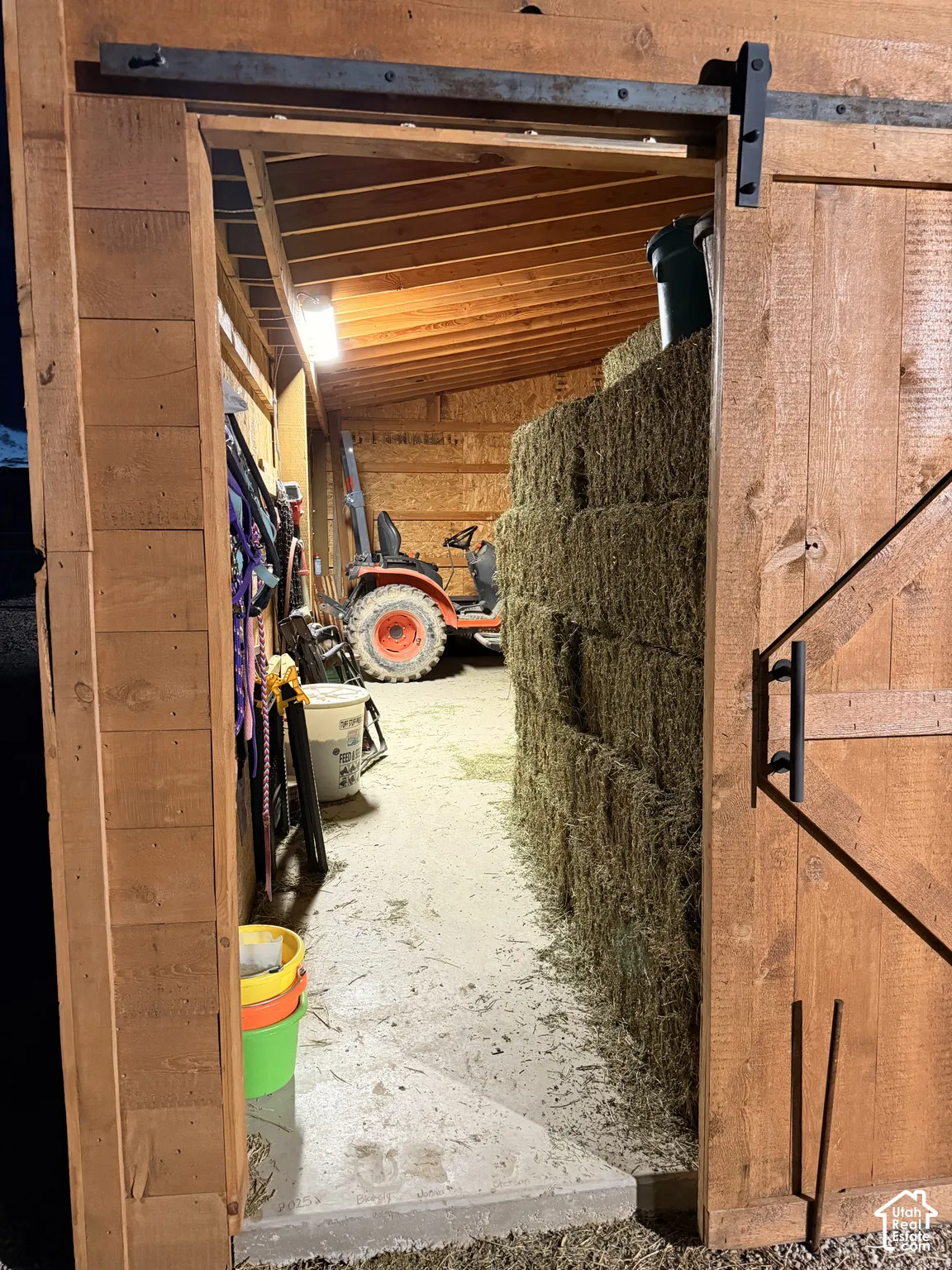 Wood-frame structure featuring exposed timber beams, sliding barn-style door with matte black hardware, and durable concrete flooring
