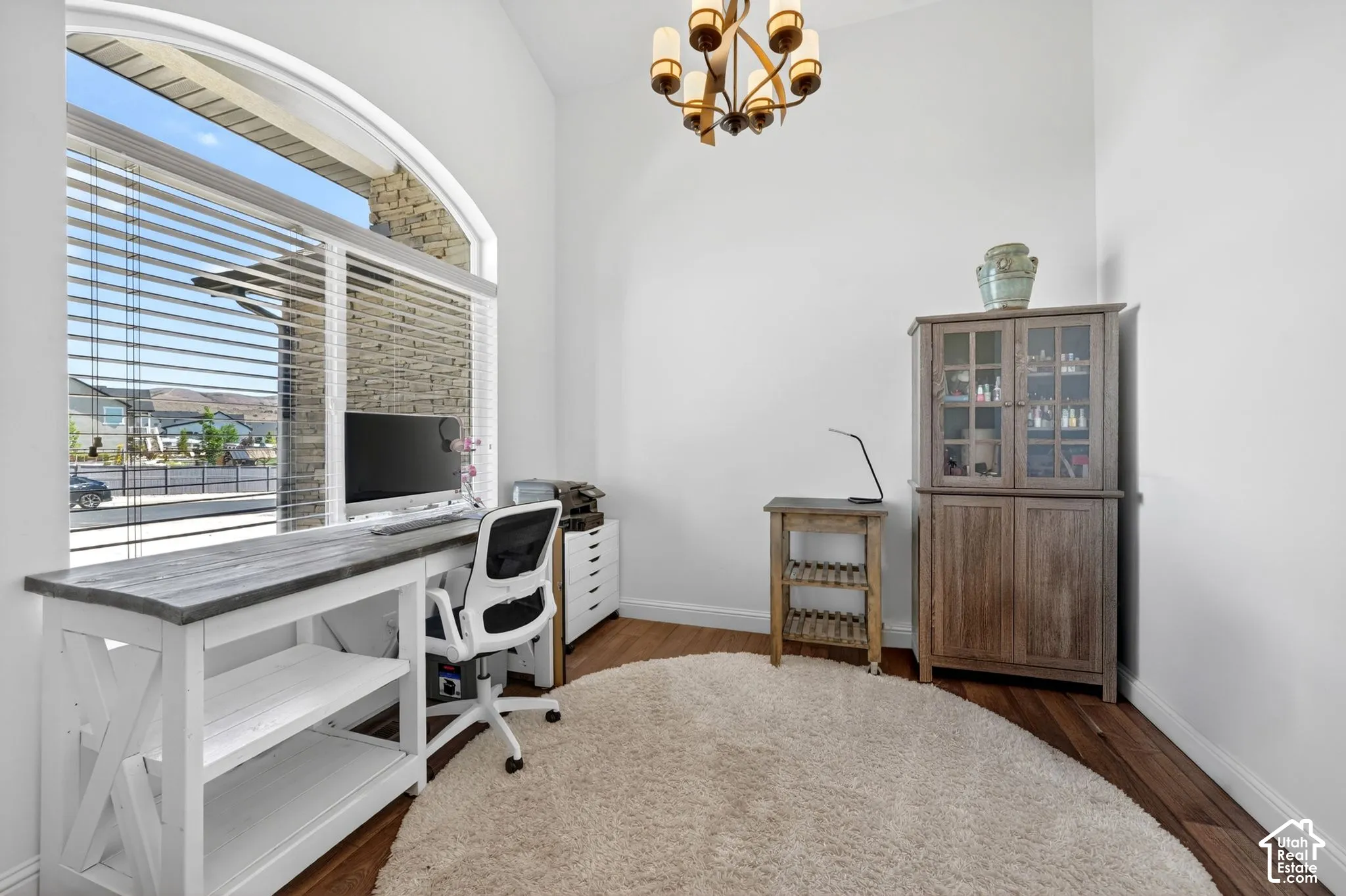 Vaulted ceiling interior space with an arched window featuring horizontal blinds