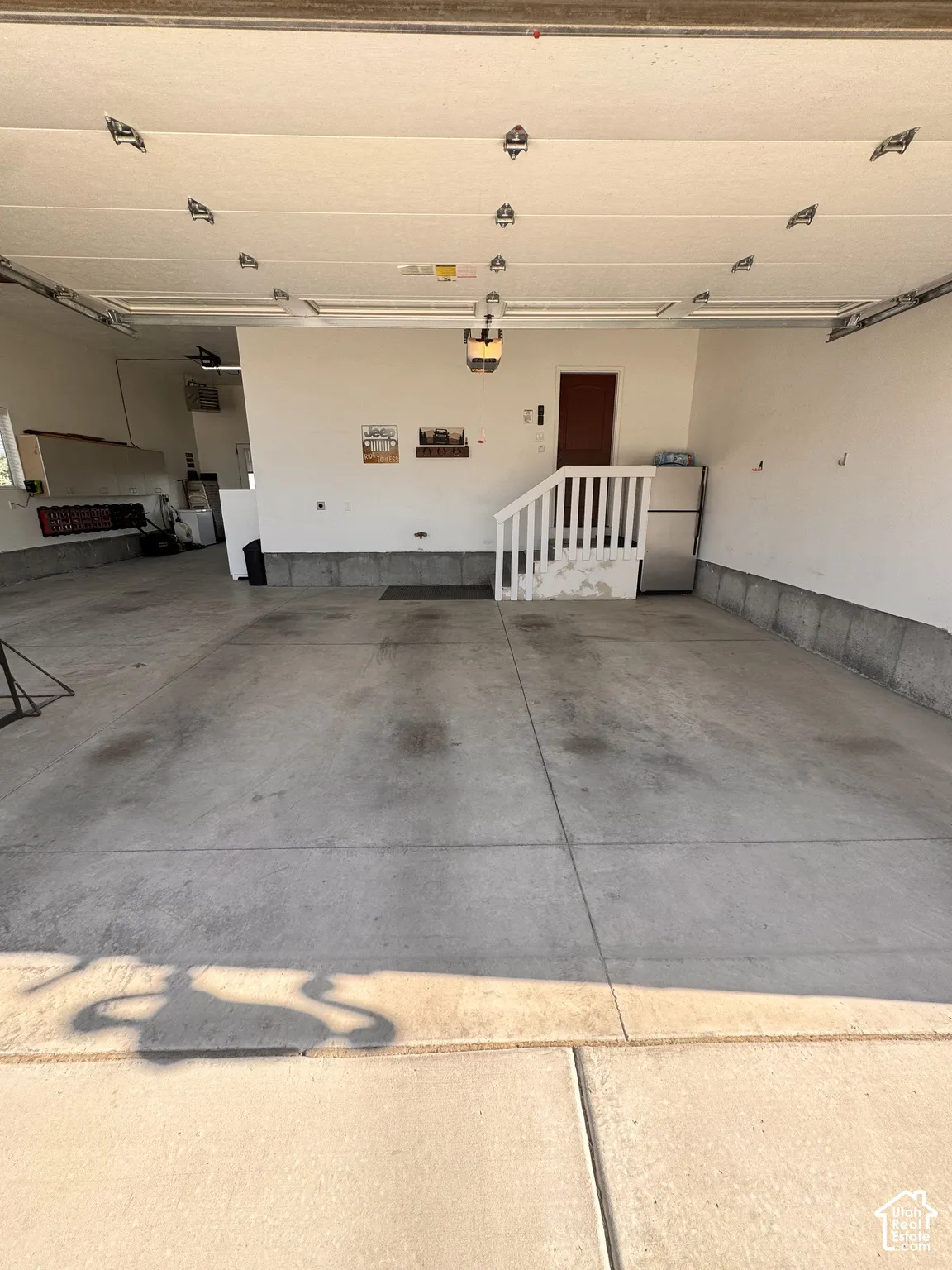 Spacious garage featuring concrete flooring, an overhead garage door, built-in shelving, and an interior access door