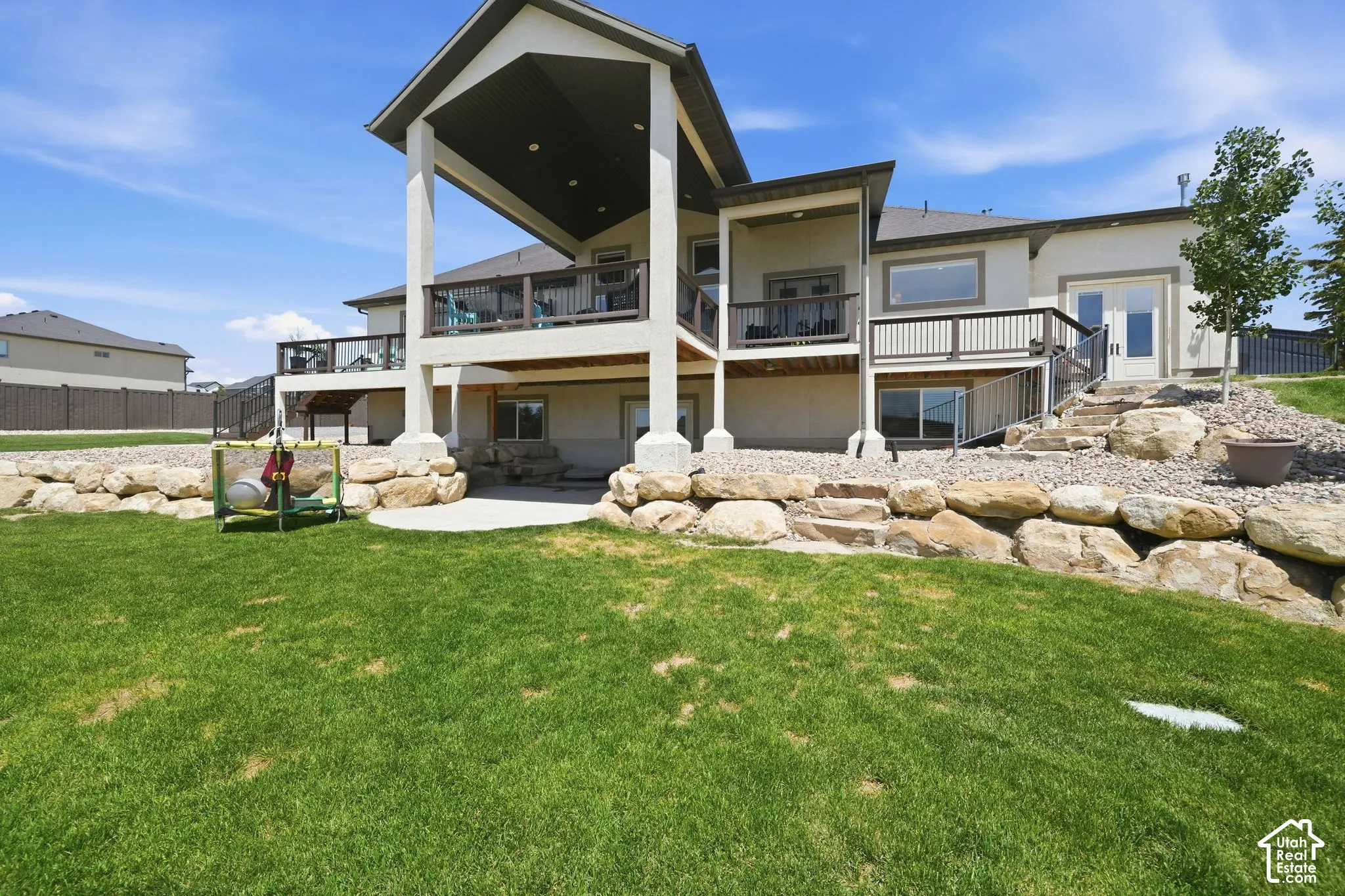 Spacious backyard with a vibrant lawn, stone retaining walls, and a multi-level deck system