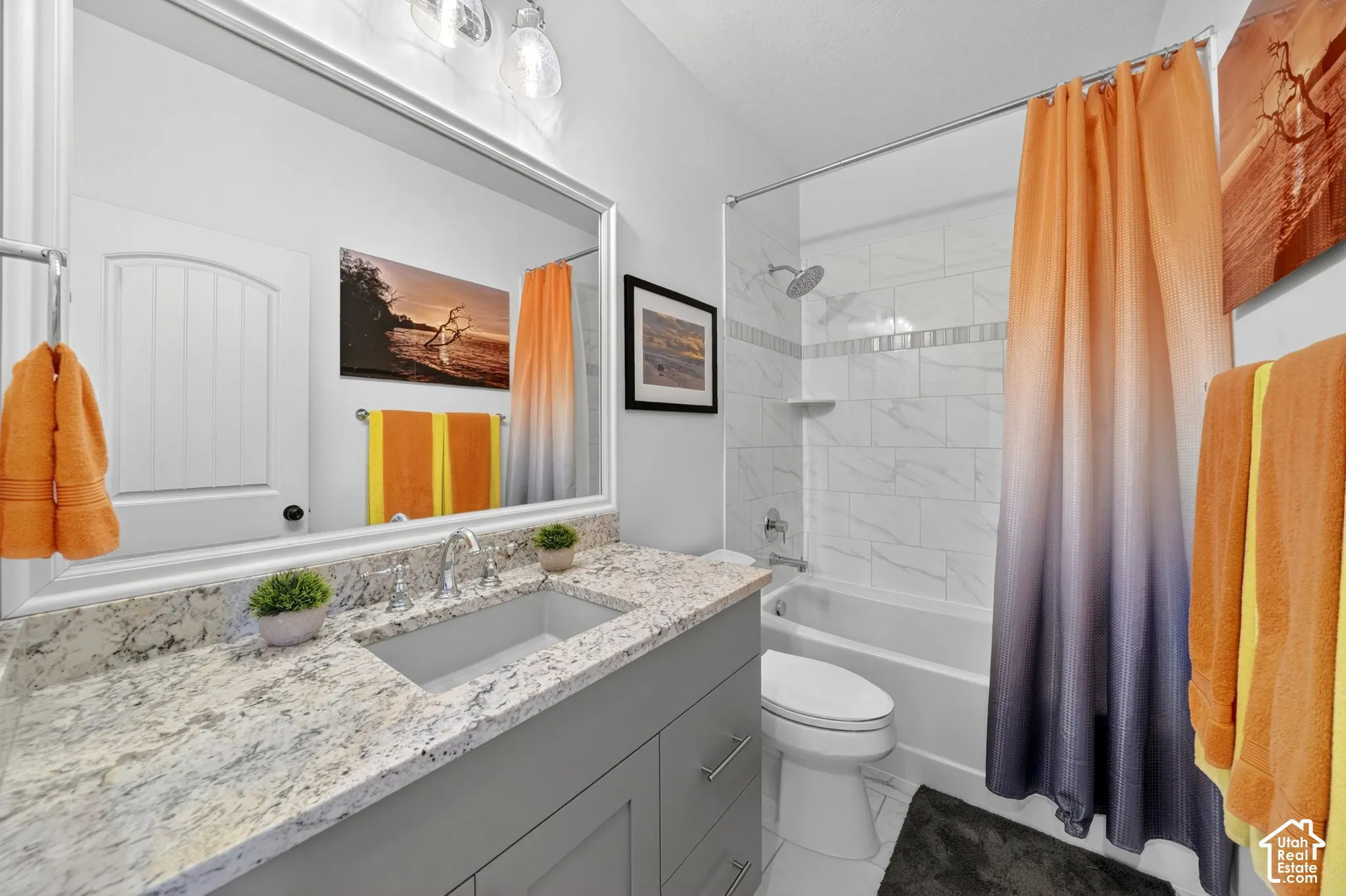 Bathroom featuring a gray vanity with a light-toned patterned countertop, an undermount sink, and a framed mirror