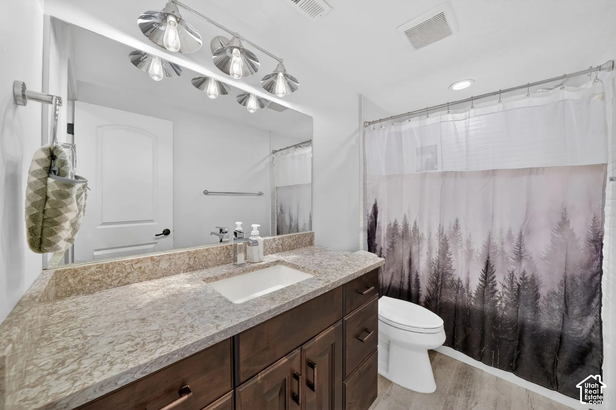 Bathroom featuring a vanity with a light-toned stone countertop, integrated rectangular sink, and dark wood-finish cabinetry