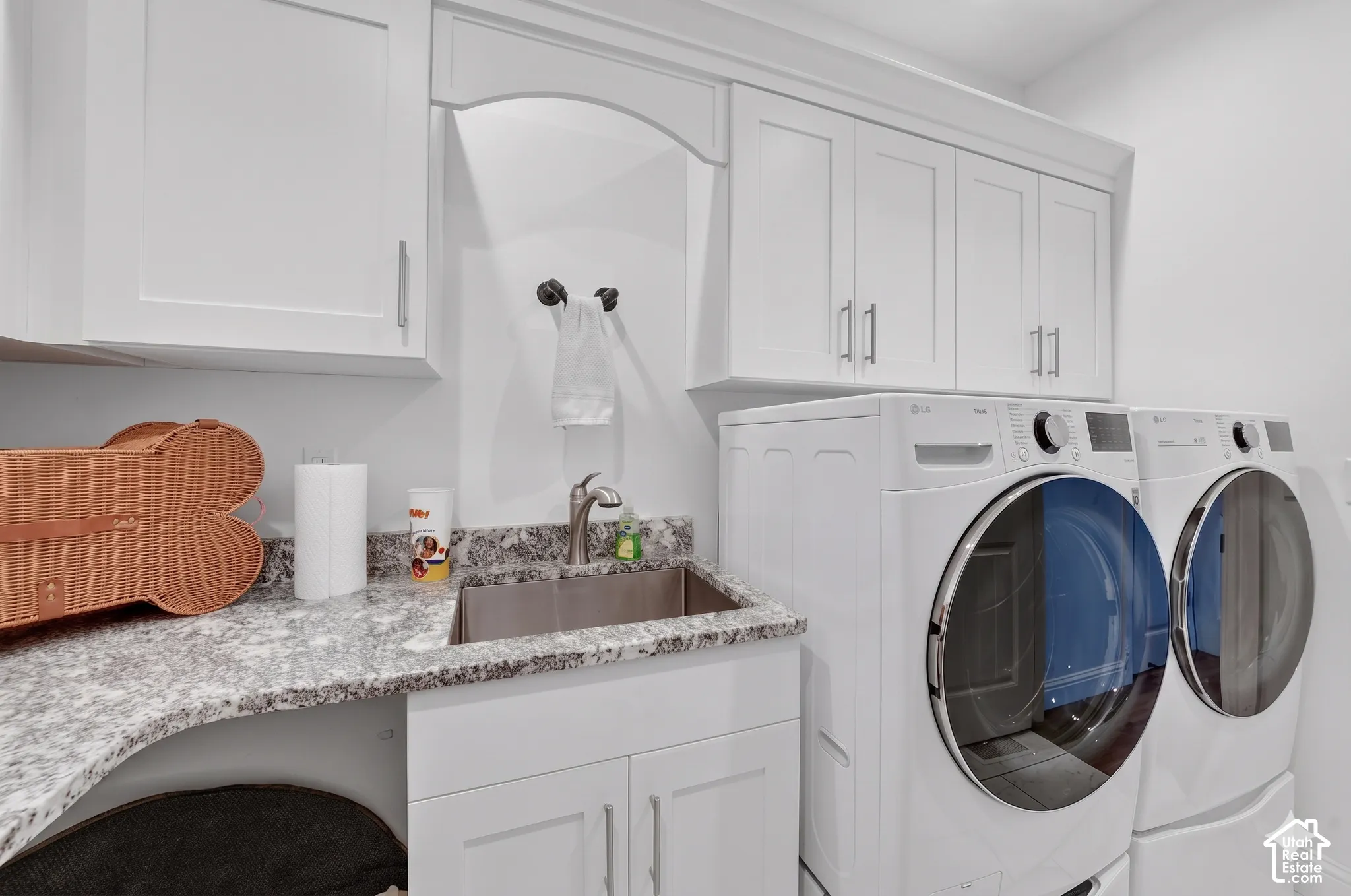 Laundry area featuring upper cabinetry, a stainless steel sink, and stone-finish countertops