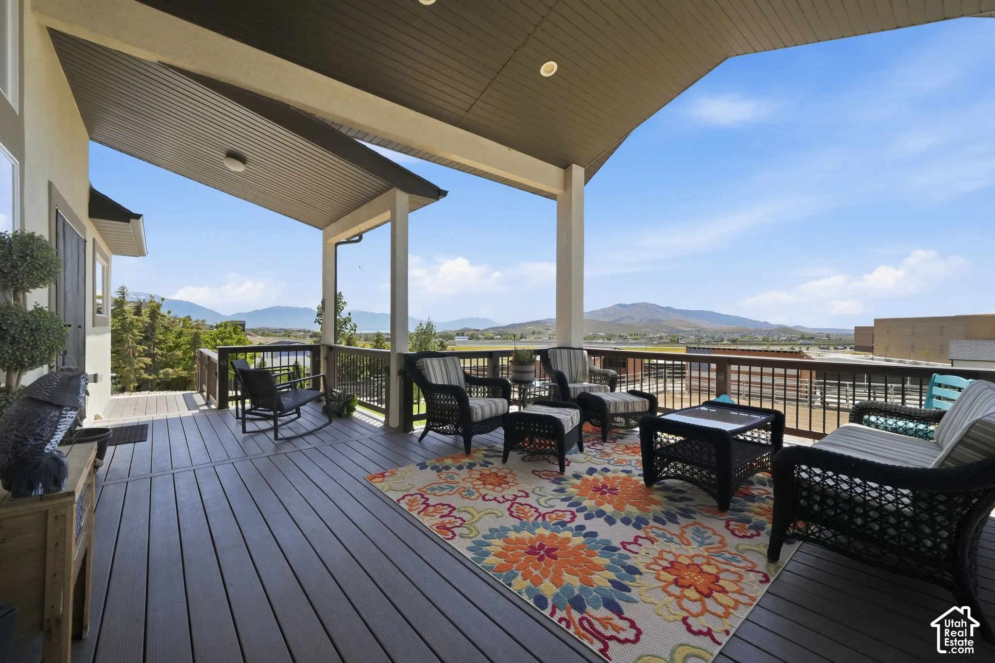Spacious covered deck featuring composite decking, recessed lighting, and a panoramic mountain backdrop