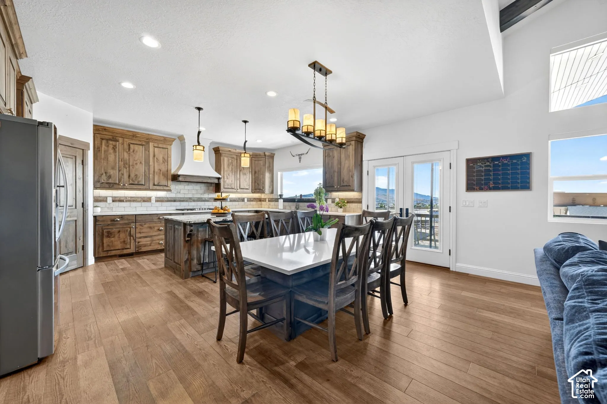 Open-concept kitchen and dining area featuring wood-finish flooring, recessed lighting, and a vaulted ceiling