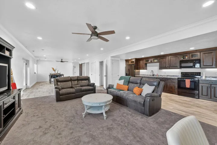 Spacious living area featuring recessed lighting, a ceiling fan, and dark wood-finish cabinetry