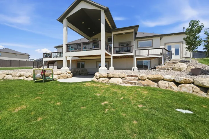 Spacious backyard with a vibrant lawn, stone retaining walls, and a multi-level deck system
