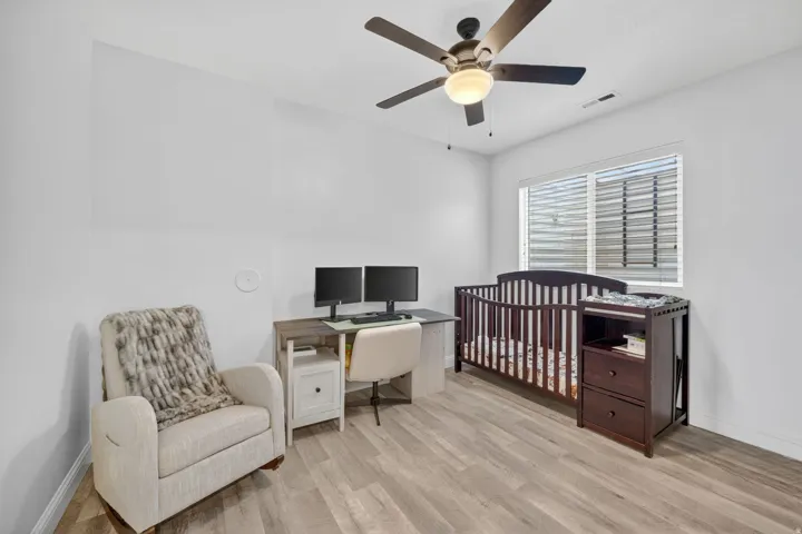 Room featuring wood-finish flooring, a ceiling fan with integrated lighting, and a window with horizontal blinds