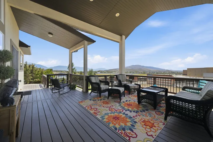Spacious covered deck featuring composite decking, recessed lighting, and a panoramic mountain backdrop