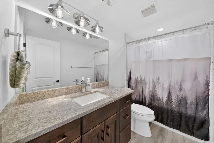 Bathroom featuring a vanity with a light-toned stone countertop, integrated rectangular sink, and dark wood-finish cabinetry
