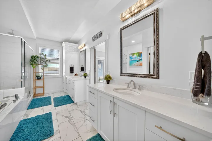 Bright bathroom featuring dual vanity with stone countertops, modern cabinetry, and individual framed mirrors