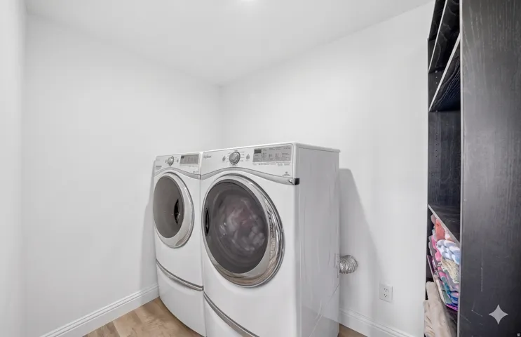 Dedicated laundry area featuring wood-finish flooring and white baseboards