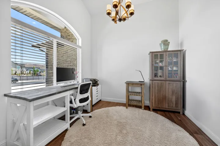 Vaulted ceiling interior space with an arched window featuring horizontal blinds