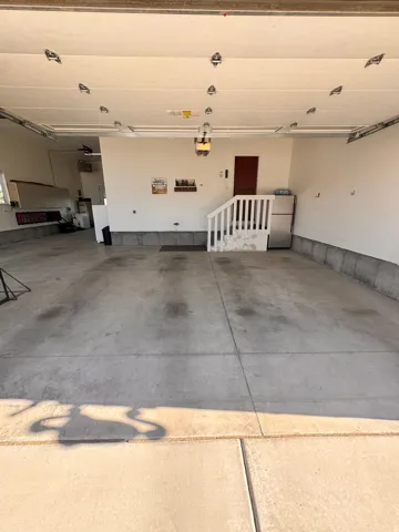 Spacious garage featuring concrete flooring, an overhead garage door, built-in shelving, and an interior access door
