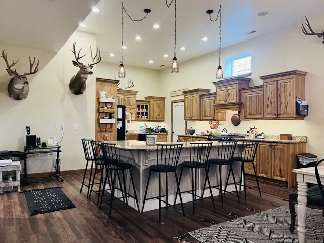 Spacious kitchen featuring warm wood cabinetry, granite-style countertops, and a large central island with seating