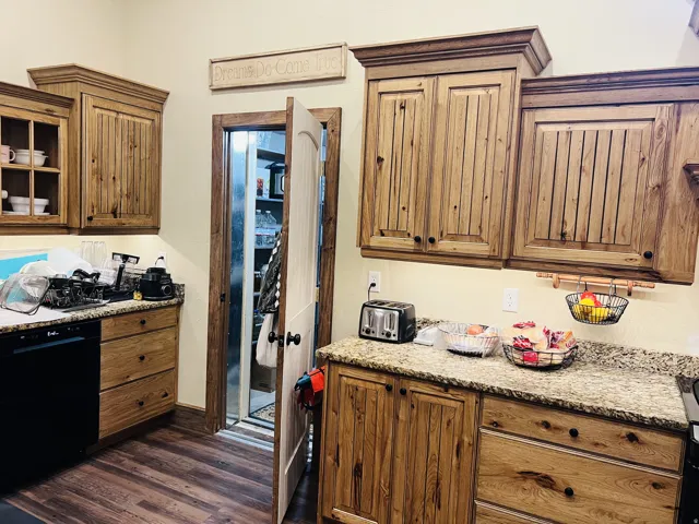 Kitchen featuring wood-finish cabinetry, granite countertops, and wood-finish flooring