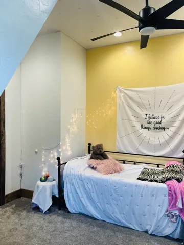Room featuring textured walls, a ceiling fan with integrated lighting, and carpeted flooring