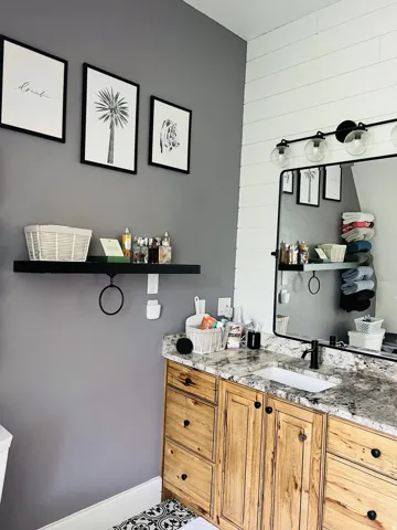 Bathroom vanity featuring a granite-style countertop, undermount sink, and wood-finish cabinetry with black hardware