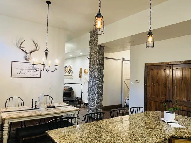 Open-concept living space featuring a granite countertop island, rustic wood-finish cabinetry, and industrial-style pendant lighting