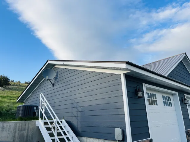 Exterior featuring horizontal siding, white trim, a metal roof, and a garage door with window inserts