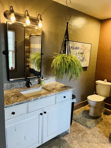 White vanity with dark hardware, stone countertop, and an undermount sink