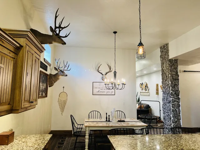 Dining area featuring a black metal chandelier, stone accent column, and wood-finish flooring