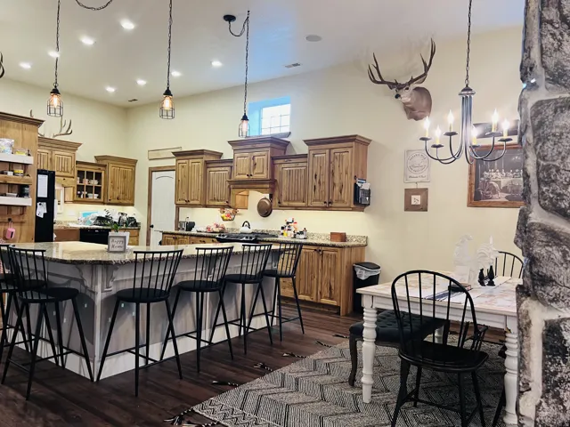 Open-concept kitchen featuring light-toned cabinetry, granite countertops, and a large central island with seating